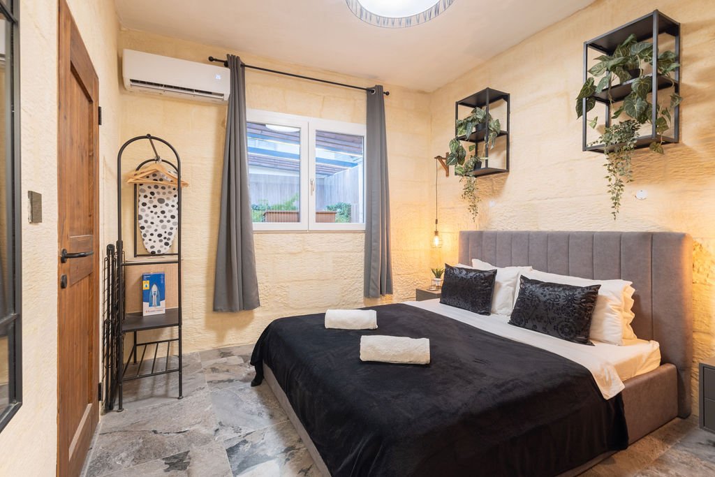 Queen-size bedroom with natural limestone walls at The Retreat in Gozo