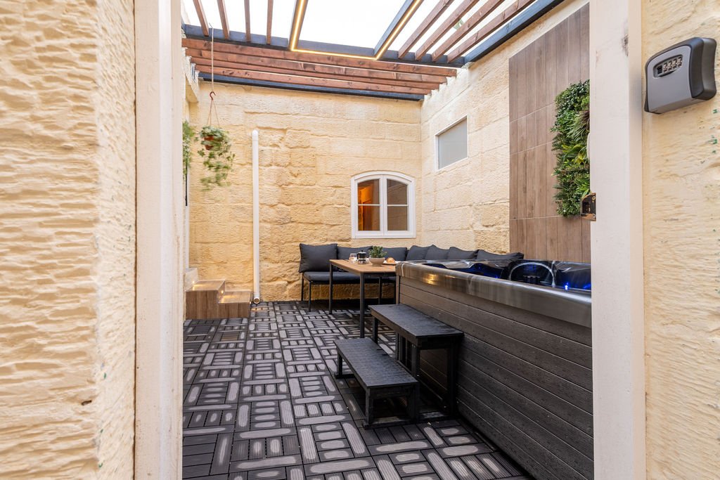 Traditional stone courtyard with seating and a private hot tub at The Retreat